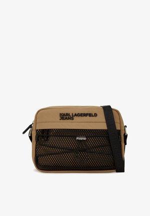 Vaaleanruskea viestintälaukku, jossa on musta verkotasku, sileä kangas, mustat korostukset ja logo. Mukana säädettävä hihna käytön helpottamiseksi.