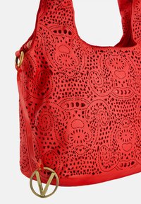 Rote perforierte Lederhandtasche mit filigranen Durchbruchsdetails, glatter Textur und einem goldenen runden Logoakzent. Verstellbarer Gurt im Lieferumfang enthalten.