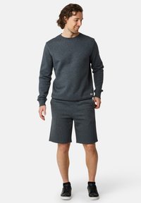 Szary sweatshirt z okrągłym dekoltem zestawiony z dopasowanymi szortami, wykonany z miękkiego materiału. Outfit zawiera czarne sneakersy i charakteryzuje się prostym wzornictwem.