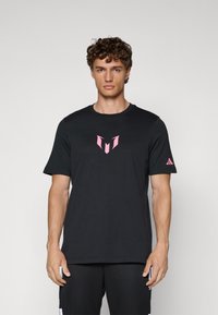 Sort atletisk t-shirt med korte ærmer, prydet med et pink logo på brystet og et Adidas emblem på ærmet. Glat stofstruktur.