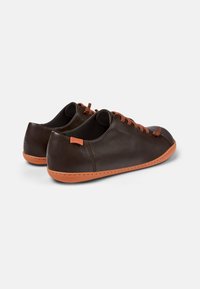 Zapatos de cuero marrón con acentos naranjas, con punteras redondas, detalles de costura y cordones planos. Textura suave y diseño minimalista.