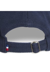Casquette en coton bleu marine avec tissu texturé, dotée d'une boucle en métal et d'un petit accent rouge, blanc et bleu sur la sangle.