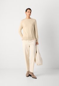 Beige Strickpullover mit geripptem Saum, cremefarbene weit geschnittene Hose, taupefarbene Stiefeletten und eine beige Tasche. Glatte Textur, modernes minimalistisches Design.