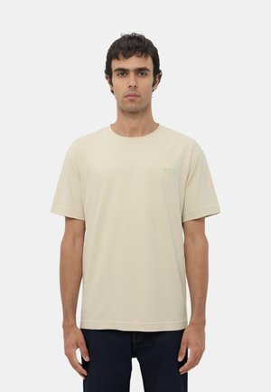 Maglietta in cotone beige con maniche corte e colletto tondo. Presenta un logo discreto sul petto sinistro. Tessuto liscio, vestibilità rilassata.