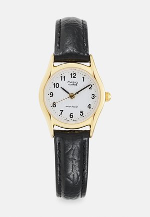Montre en quartz dorée avec un cadran blanc rond, un bracelets en cuir noir, des index noirs et des caractéristiques de résistance à l'eau.