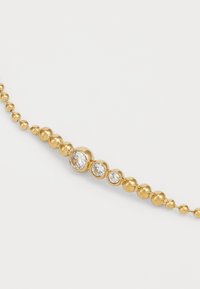 Bracciale in oro con perline a forma di sfera di diverse dimensioni, con tre pietre trasparenti incastonate nei perni più grandi per un tocco di delicatezza.