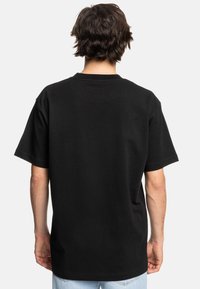 Černé bavlněné tričko s krátkým rukávem a kulatým výstřihem, s volným střihem a hladkou texturou. Bez viditelných grafik nebo vzorů.