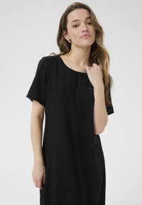 Black dress made of lightweight fabric, featuring short sleeves, a round neckline, and a relaxed fit, with minimal stitching details.