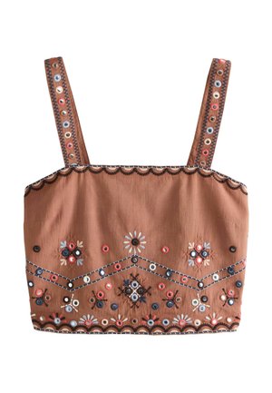 Donna che indossa un crop top marrone ricamato e shorts a vita alta abbinati con motivi floreali e geometrici colorati.