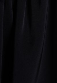 Tissu noir avec une texture lisse, présentant un drapé subtil et une légère réflexion de la lumière. Aucun motif ou accessoire visible.