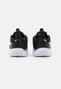 Zwarte sportieve schoenen met een bovenwerk van mesh en synthetisch materiaal, met een witte zool, gebogen ontwerp en haakjes aan de achterkant voor gemakkelijk aan- en uittrekken.