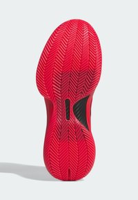 Semelle rouge de chaussure de sport avec motif en chevrons et soutien en fibre de carbone noire dans la zone de la voûte plantaire.