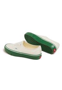 Sneakers in tela con tomaia crema, suola in gomma verde, strisce bianche laterali e etichetta rossa con logo. Presentano lacci rotondi e suola testurizzata.