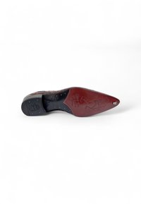 Suela de zapato de punta en cuero burdeos con acentos de goma negra. Presenta un diseño grabado y tachuelas doradas. Textura suave, forma elegante.