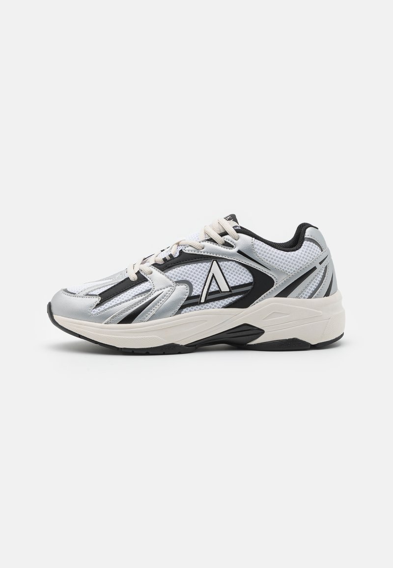 Scarpa sportiva argento e nera con sovrapposizione in rete, caratterizzata da una suola spessa, un logo prominente e lacci a contrasto per supporto e stabilità.