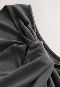 Ciemnoszary top z miękkiej tkaniny, z detalem skręconego węzła z przodu oraz prostym przeszyciem na krawędziach.