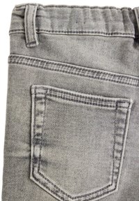 Grå denimstof, der viser et nærbillede af en baglomme med kontrast søm og en semi-fadet tekstur. Har en bæltestrop øverst.