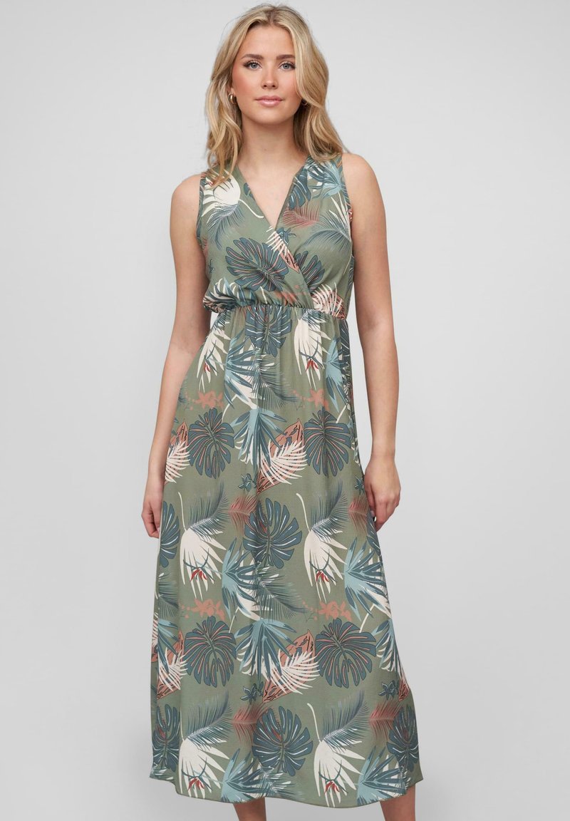 Maxi dress in green fabric featuring a tropical leaf pattern in blue, white, and pink. V-neck with an elastic waist and sleeveless design.