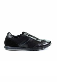 Schwarzer Sportschuh aus Leder und Mesh, mit einer strukturierten Oberseite, Schnürsenkeln und einer gepolsterten Sohle. An der Seite befindet sich ein geprägtes Markendesign.