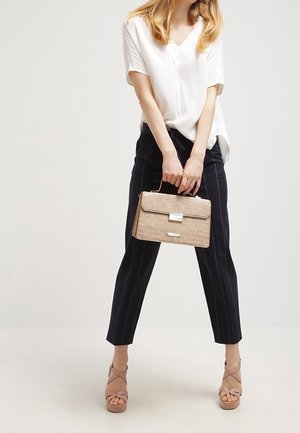 Béžová strukturovaná kabelka s texturovaným povrchem a stříbrnou sponou, doplněná bílou blůzou, tmavě modrými kalhotami s proužky a tělovými sandály na platformě.