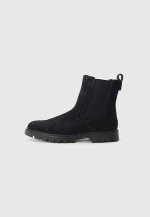 Bota Chelsea de ante negro con parte superior texturizada, paneles laterales elásticos, tirador y suela de goma resistente para mayor tracción.