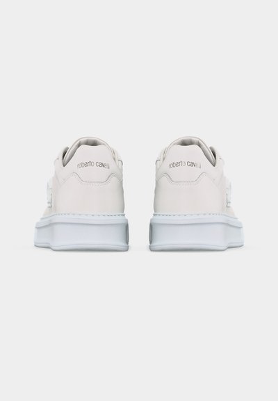 Ζευγάρι λευκά δερμάτινα αθλητικά παπούτσια με παχιά λευκή σόλα, φαίνονται από πίσω, με το λογότυπο "roberto cavalli" στα τακούνια.