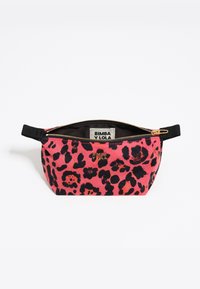 Bolso con estampado de leopardo en rosa y negro, con cremallera y correa negra, y logo dorado de "Bimba y Lola", parcialmente abierto mostrando la etiqueta interior de la marca.