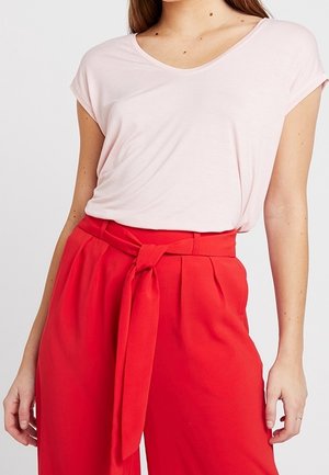 T-shirt rosa chiaro a maniche corte con scollo a V abbinato a pantaloni rossi a vita alta con un fiocco legato in vita e frontale plissettato.