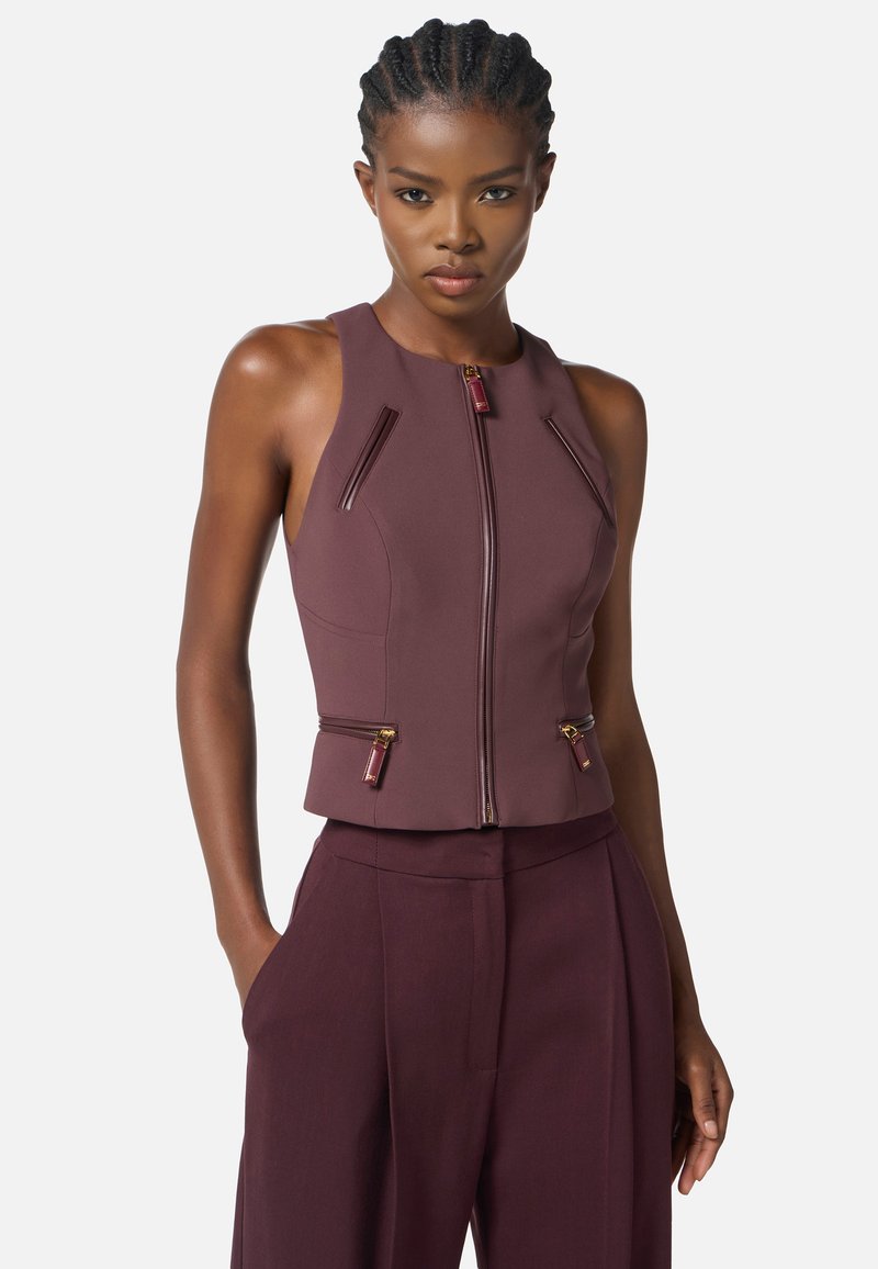 Top senza maniche bordeaux con collo alto, zip frontale e tasche with zip angolate; design aderente e texture liscia.