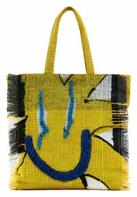 Żółta pleciona torba na ramię z grafiką uśmiechniętej twarzy w niebieskich i czarnych akcentach. Dwie mocne rączki do noszenia. Teksturowane wykończenie.