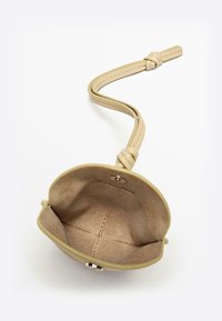 Portamonete in pelle beige con forma curva, esterno liscio e singolo cinturino. Interno morbido con dettagli cuciti. Chiusura a scatto.