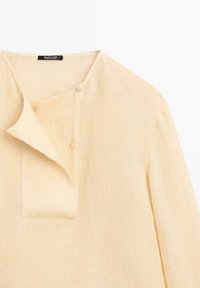 Beiger Strickpullover mit rundem Ausschnitt, asymmetrischer Knopfleiste und langen Ärmeln, Label „Massimo Dutti“ innen am Kragen sichtbar.