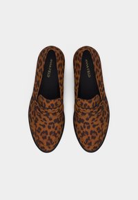 Ζεύγος καφέ και μαύρων μοκασίνια με λεοπάρ εκτύπωση, χωρίς κορδόνια, με μαύρες εσωτερικές σόλες και την επιγραφή "ANNA FIELD" εσωτερικά.