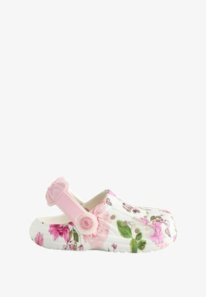 Zoccoli con motivo floreale in bianco e rosa, dotati di una fascia rosa regolabile con dettaglio a fiocco. Realizzati in materiale flessibile con fori di ventilazione.