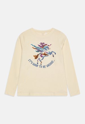 Langærmet cremet T-shirt med et multikolor sequin-unicorn grafik og teksten "Det er godt at være unik" nedenfor.