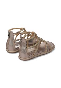 Sandalias metálicas en color rosa dorado con correas entrelazadas y un cierre de cremallera en la parte trasera. La suela presenta un sutil acento de brillo.