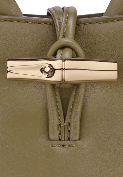 Olive green leather handbag featuring a gold clasp, sleek design, and detailed stitching near the closure for enhanced texture.