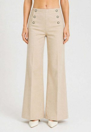 Pantaloni beige a vita alta e gamba larga con sei bottoni decorativi, indossati con tacchi bianchi a punta, mostrati dalla vita ai piedi.