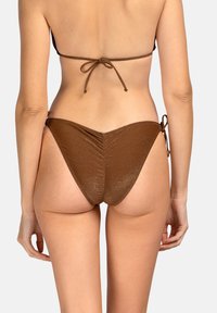 Brązowe, błyszczące majtki bikini z marszczeniami, cienkimi wiązaniami po bokach i minimalnym zakryciem, wykonane z gładkiego, teksturowanego materiału.