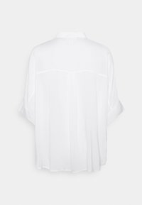 Blusa bianca a maniche corte con colletto, tessuto morbido, vestibilità comoda e delicati dettagli di cucitura lungo la schiena.