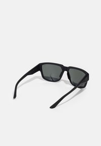 Ochelari de soare negri cu ramă pătrată, lentile gri, finisaj mat și brațe drepte, elegante. Prezintă o marcă minimă pe lateral.