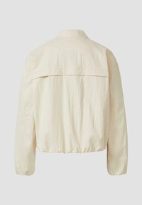 Leichtgewichtige, cremefarbene Jacke mit langen Ärmeln, elastischem Saum und einer Rückenpasse, von hinten gezeigt.