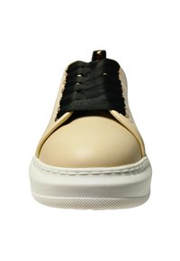 Lichtbeige sneaker met een ronde neus, witte zool en zwarte veters. Heeft een leerachtige uitstraling en opvallende stikselaccenten.