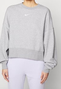 Grå kortärmad sweatshirt tillverkad av mjuk bomullsblandning, med rund halsringning och ribbad nederkant. Inkluderar en liten vit Nike-logotyp på bröstet.