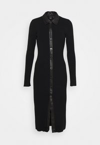 Svart klänning i ribbat stickat material med en knäppning i konstläder, långa ärmar och en slits i botten.