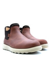 Bottes chelsea en cuir marron avec un panneau latéral élastique noir texturé et une semelle en caoutchouc blanche ondulée. Fini lisse et design à bout arrondi.