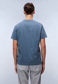 T-shirt en coton bleu à manches courtes et col rond. Texture lisse avec une coupe droite, présenté de dos. Design minimaliste.