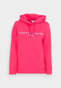 Rosa Kapuzenpullover aus weichem Stoff, mit weißem Logotext und kleinem Logoakzent am Ärmel, mit Kordelzug am Ausschnitt.