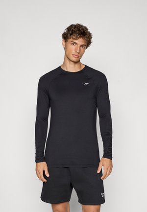 Maglietta sportiva nera a maniche lunghe realizzata in materiale elastico, con scollatura rotonda e maniche raglan; presenta un piccolo logo bianco sul petto.