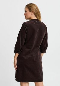 Brown corduroy dress with three-quarter sleeves, buttoned cuffs, and a straight cut. Smooth texture and a simple back design.